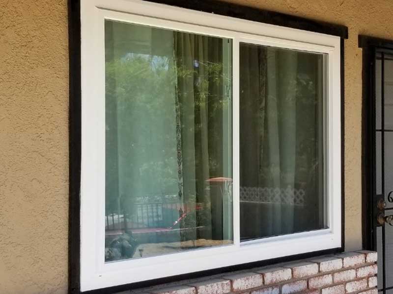 Close up of a white, slider window on the side of a home