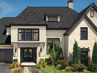 Front view of a large beige home with black GAF shingles on the roof