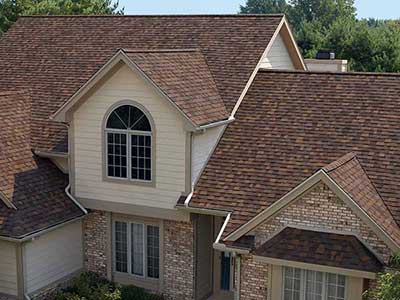 Front view of a large mid-class home with red-ish brown Owens Corning shingles on its roof